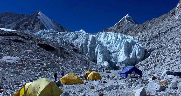 Un camp de base avec des tentes colorées entouré de montagnes glacées.