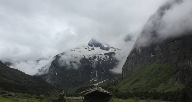 Un paysage montagneux brumeux avec des sommets enneigés.