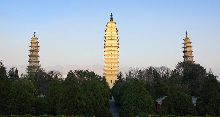 Las Tres Pagodas elevándose sobre una densa vegetación con montañas brumosas al fondo.