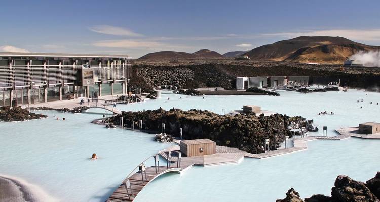 Bezoekers genieten in het dampende melkachtige water van de Blue Lagoon omringd door lavalanden.