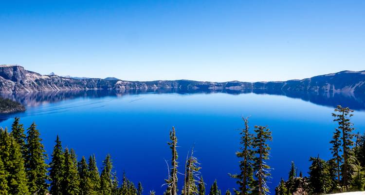 Lac bleu clair entouré de montagnes et d'arbres.
