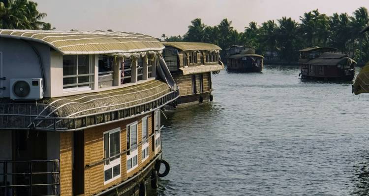 Waterweg gevuld met woonboten te midden van tropische omgeving.