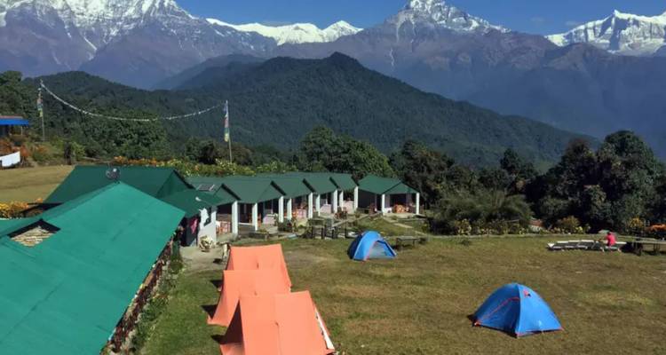 Campingplatz mit Zelten und Gebäuden vor einer bergigen Kulisse.