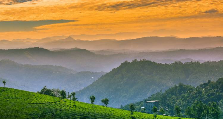 Een adembenemend uitzicht op gelaagde heuvels onder een levendige, kleurrijke hemel.