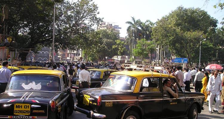 Belebte Stadtstraße mit gelben Taxis und einer großen Menschenmenge.