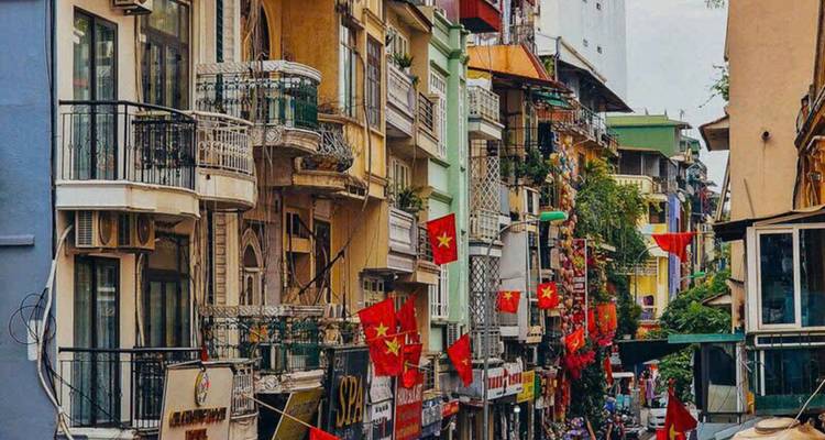 Narrow urban street with colorful buildings and flags.