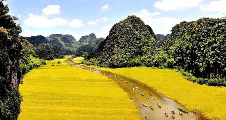Boats on a river between lush green mountains.