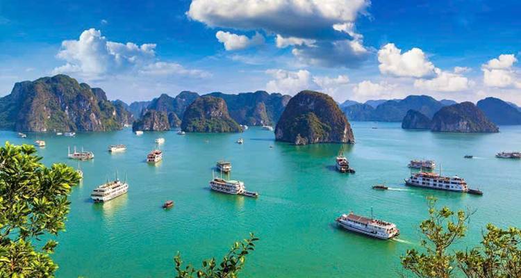 Boats sailing between large limestone karsts on emerald waters.
