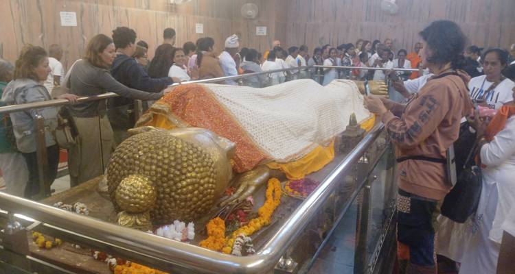 Eine Gruppe von Menschen versammelt um eine liegende Buddha-Statue.