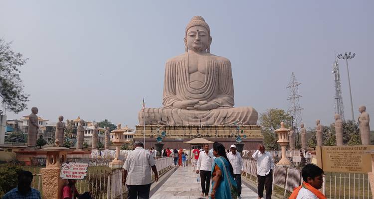 Eine große Buddha-Statue in einem Innenhof mit Besuchern.