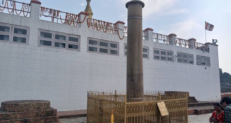 Eine historische Stätte mit einer Säule und Besuchern vor einem Gebäude.