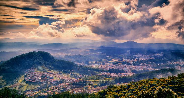 Ciel dramatique au-dessus d'une ville étalée dans les collines.