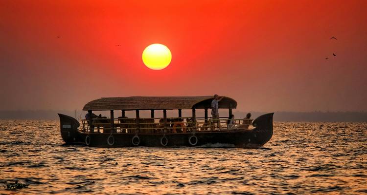 Woonboot op een meer met zonsondergang op de achtergrond.