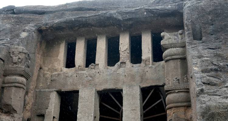 Oude in de rots uitgehouwen tempelfacade met zuilen.