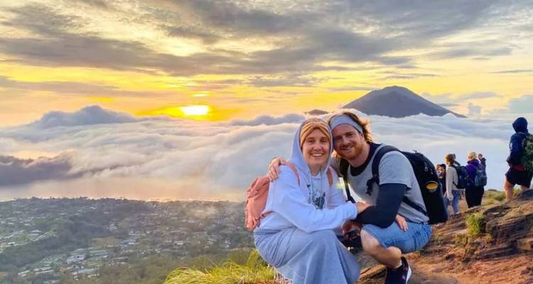 Couple avec une vue panoramique sur les montagnes et les nuages au coucher du soleil.