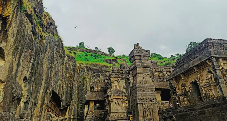In de rots uitgehouwen tempelcomplex te midden van groen en ruw terrein.