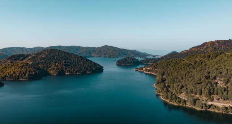 Large panorama de drone d'un réservoir bleu profond serpentant entre les crêtes boisées.