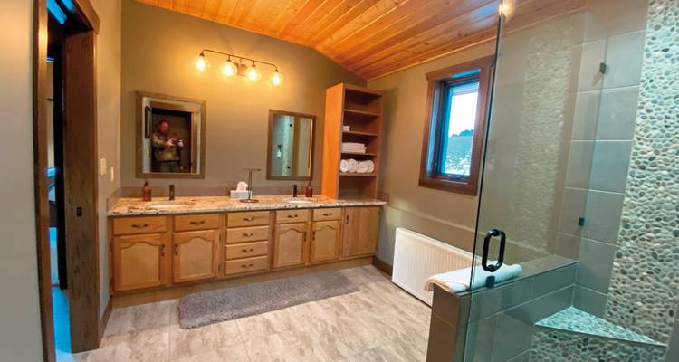 Modern bathroom with large mirrors and wooden accents.