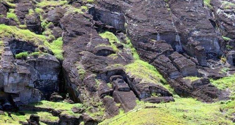 Primer plano de acantilados volcánicos escarpados salpicados de vegetación verde en la Isla de Pascua.