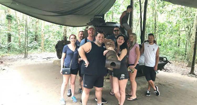 Groepsfoto in het Cu Chi Tunnels gebied met een militair voertuig.