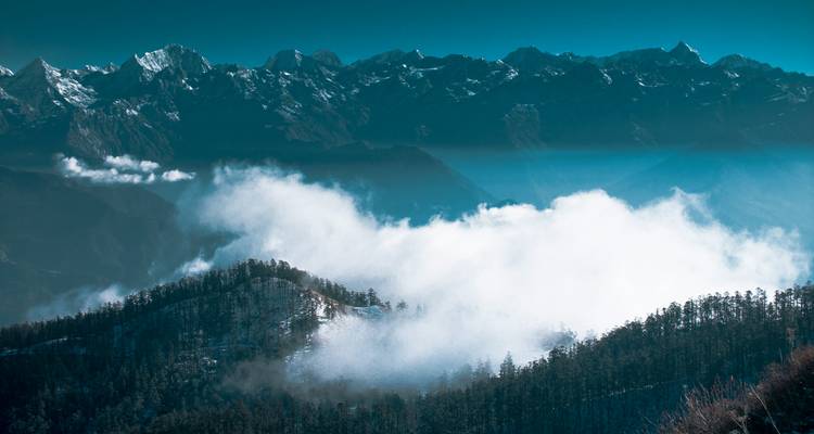 Wolken, die über schneebedeckten Berggipfeln schweben.