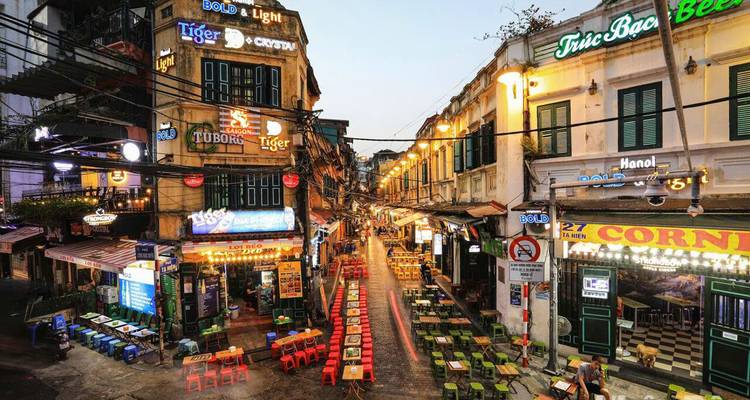 Street view with colorful signs and outdoor seating in Hanoi.