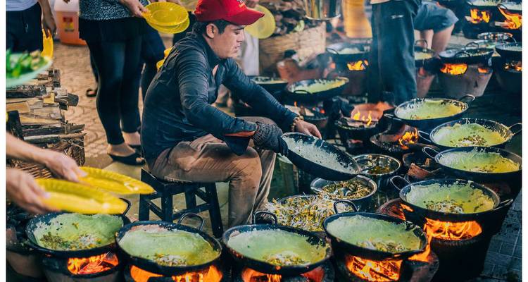 Street food preparation with multiple open flames and cooking activities.