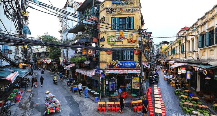 Lively street with colorful signs and small outdoor seating areas.