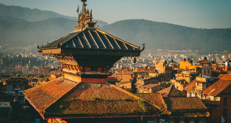 Temple roof with lush mountains in the background.