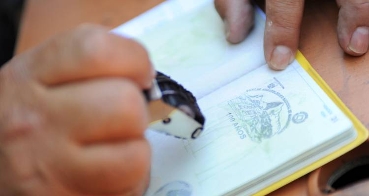 Gros plan d'une main qui tamponne un passeport.