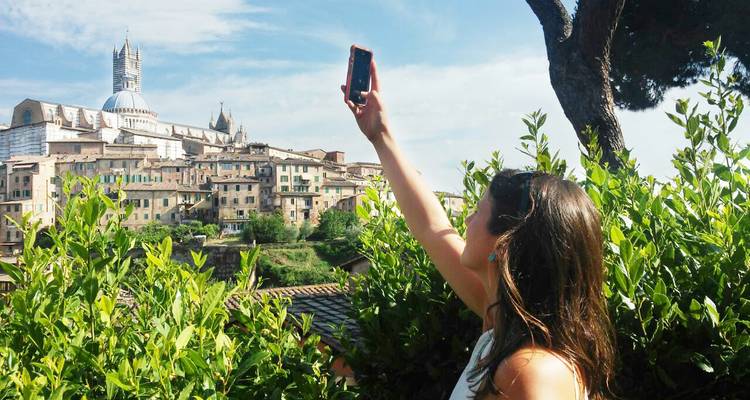 A woman taking a selfie with a view of city buildings and a cathedral.