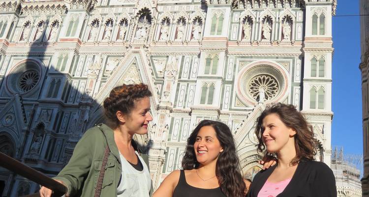 Three women standing in front of ornate architecture.