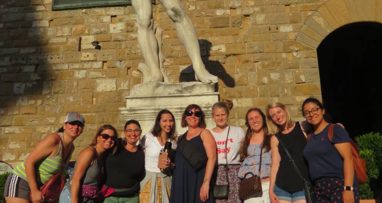 A group of people posing in front of a statue and stone buildings.