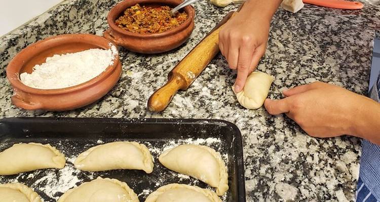 Personne préparant des empanadas traditionnelles sur un comptoir en marbre.
