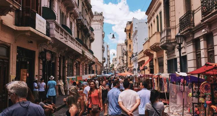 Marché extérieur animé avec des gens qui marchent entre les étals de rue.