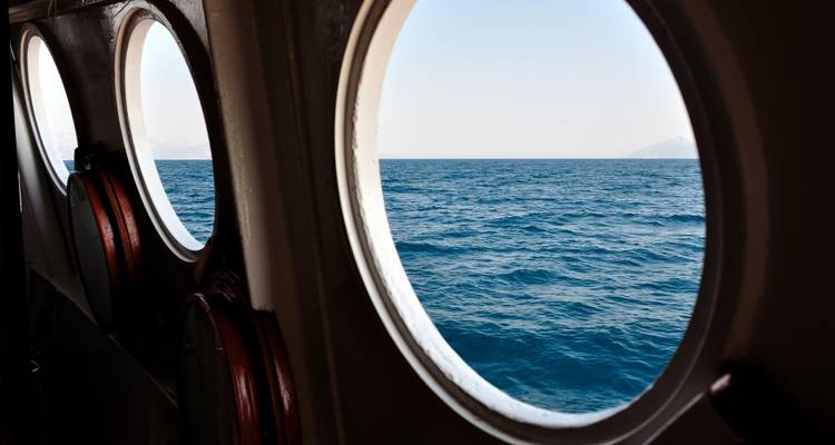 View of the ocean through the round portholes of a ship.