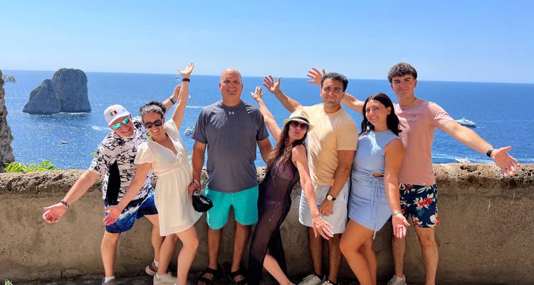 Grupo de personas posando con una vista escénica del mar.