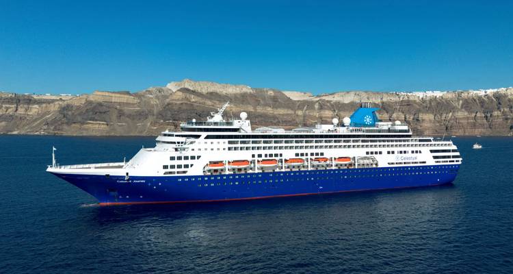 Kreuzfahrtschiff segelt vor bergiger Kulisse.