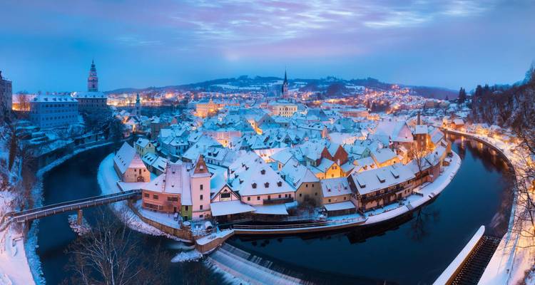 Panoramisch uitzicht op Cesky Krumlov in de winterse schemering met het sneeuwbedekte middeleeuwse stadje in een rivierbocht.