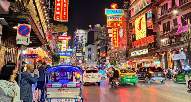Busy street at night with neon signs and vehicles.