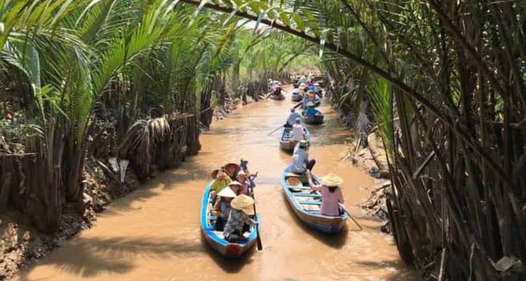 Menschen die boten roeien door een smalle waterweg.