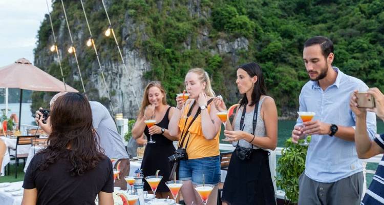 Mensen die genieten van cocktails op een boot bij rotsachtige kliffen.