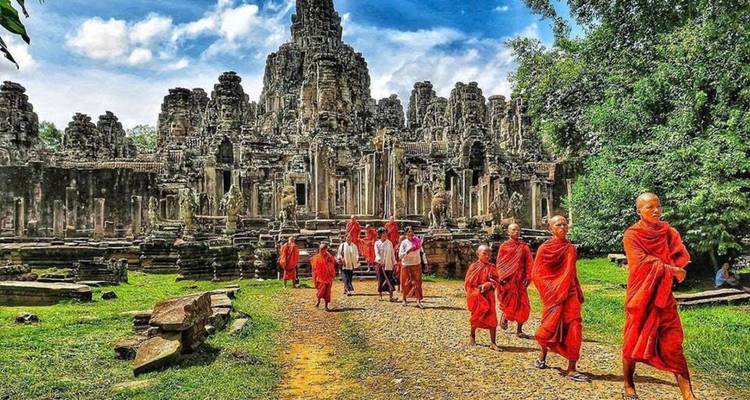 Monniken en toeristen lopen voor oude ruïnes.