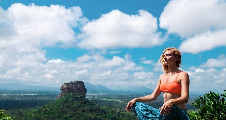 Person in meditation with Sigiriya Rock in the background.