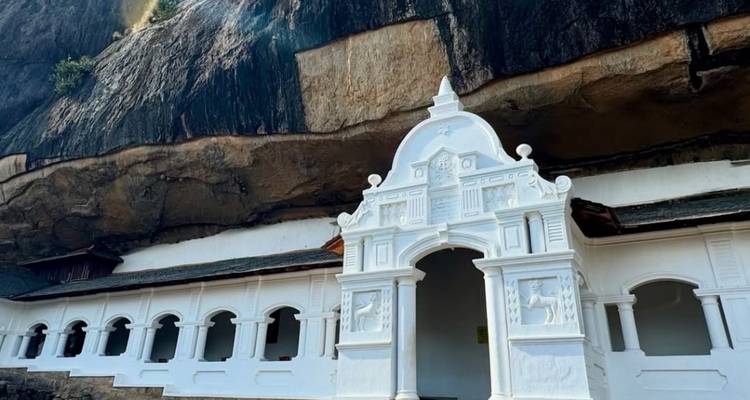 Facade of a white temple set against a cliff backdrop.