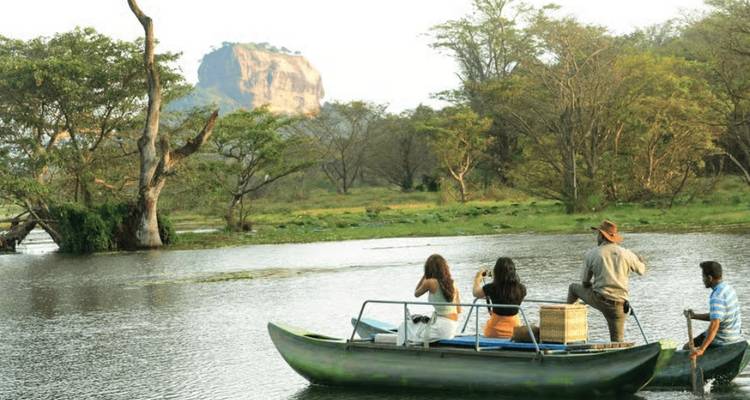Group on a boat tour with Sigiriya Rock in the background.
