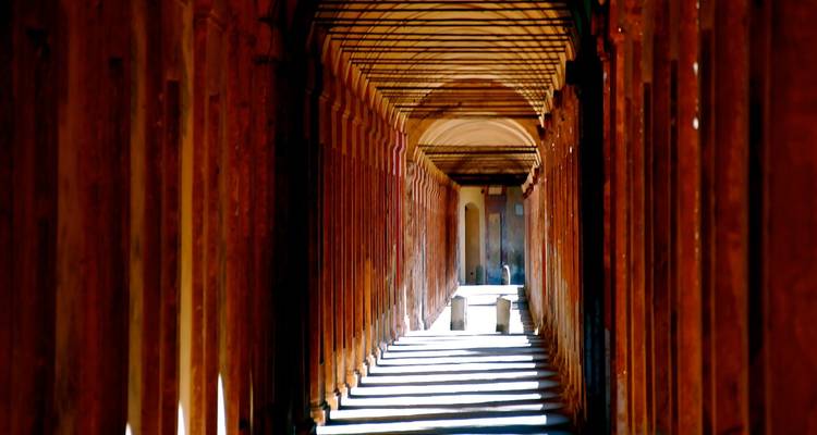 Sonnenbeschienener Korridor mit Bögen, die ein Muster aus Schatten erzeugen.