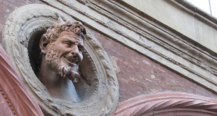 Steinmetzarbeit eines Gesichts an einer Gebäudefassade.