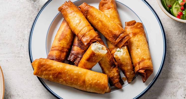 Plate of crispy golden Turkish cigar börek pastries arranged on a white dish.