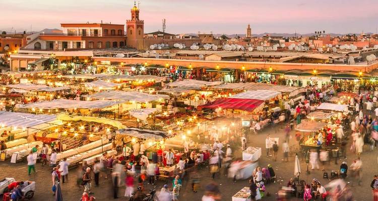 Bruisende marktscène tijdens de schemering met veel kramen en mensen.